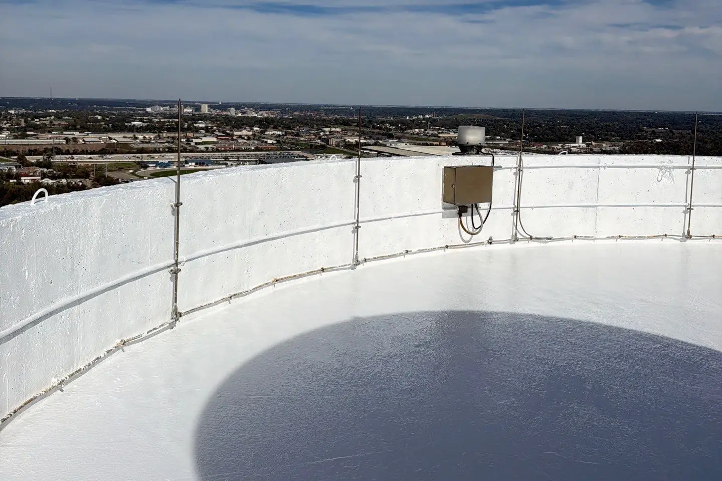 Freshly coated white silicone roof on top of a 220-foot grain silo in Cedar Rapids, Iowa, with the city skyline behind