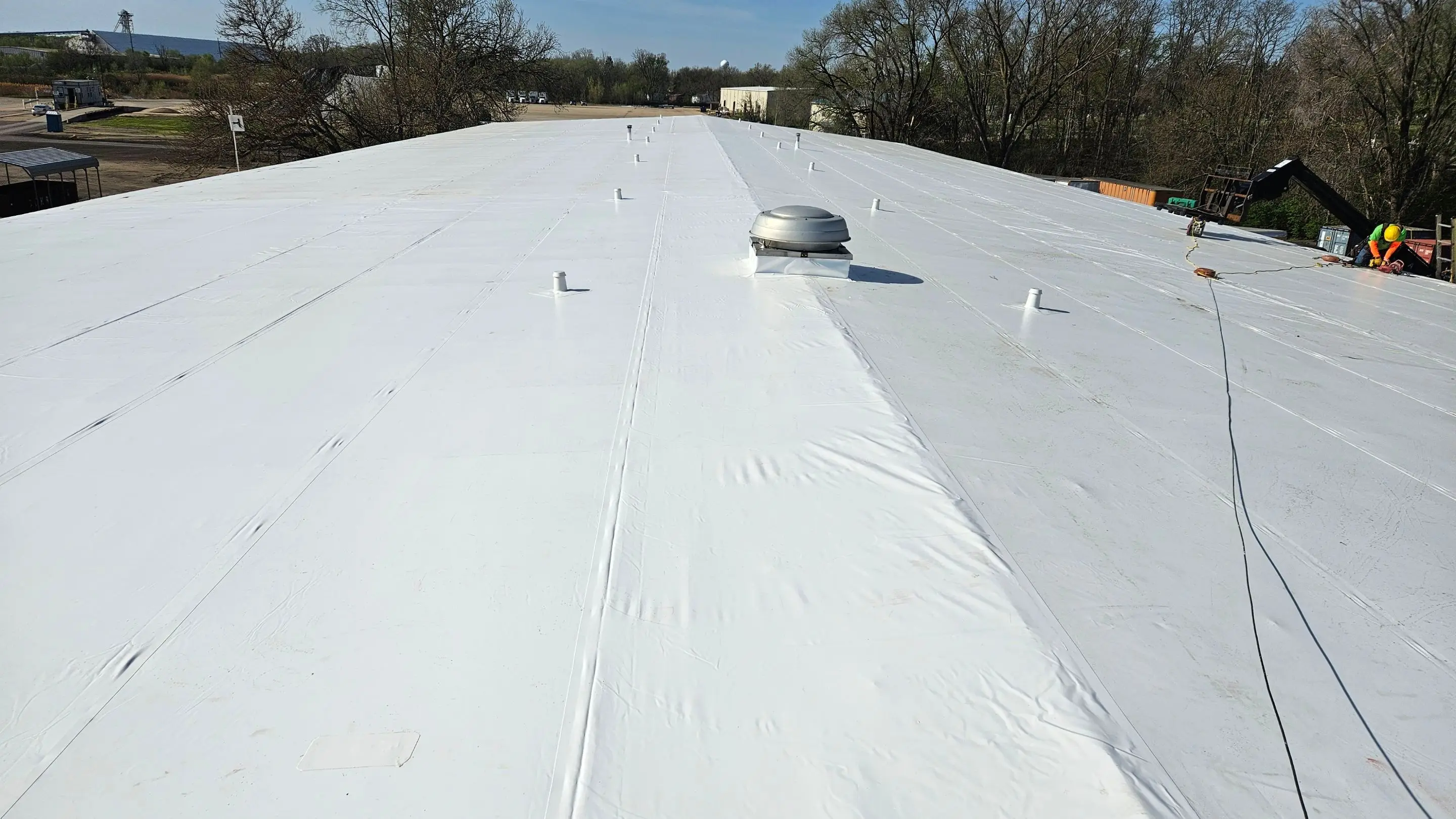 Wide white Duro-Last PVC roof on an industrial warehouse in Camanche, Iowa, under a clear sky