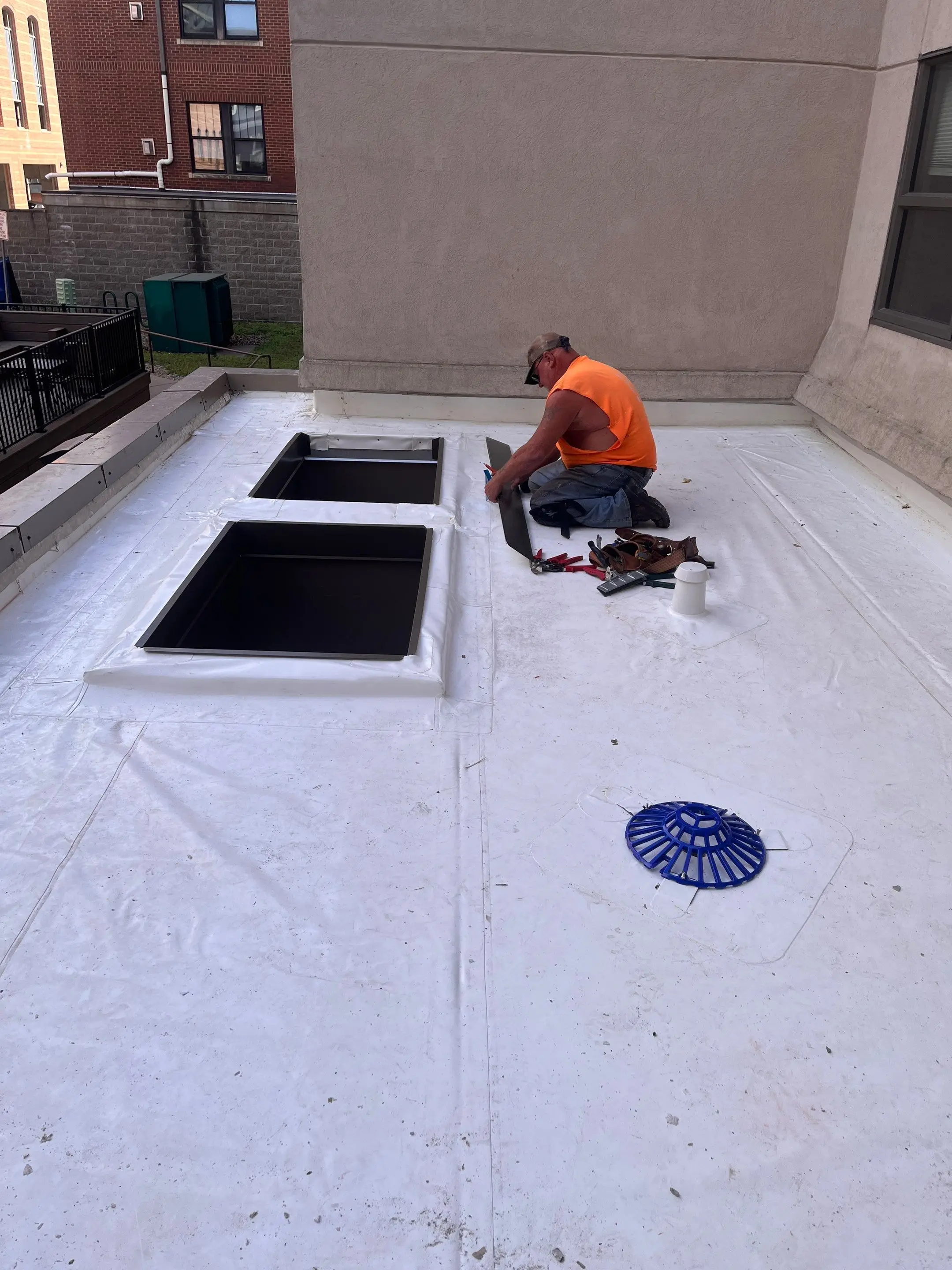 Roofer detailing skylight curbs on a new white Duro-Last roof at a high-rise in Iowa City, Iowa