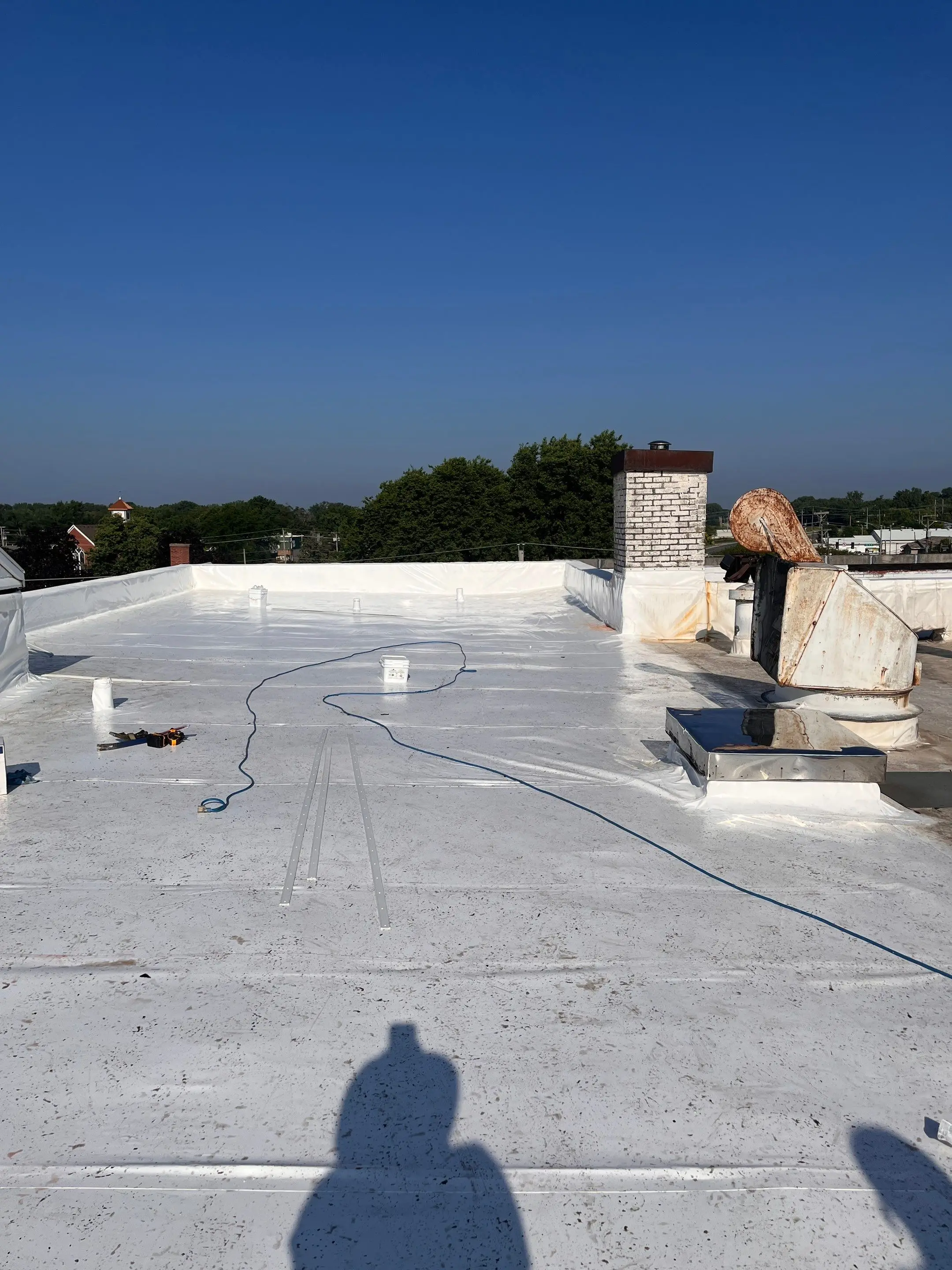 Crew installing a white Duro-Last roof on an auto dealership in Milan, Illinois