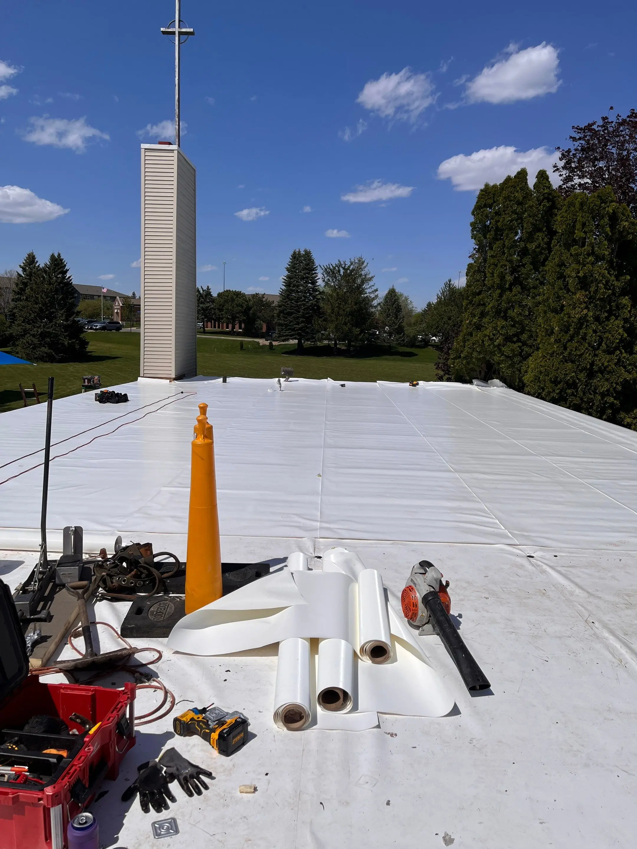 Crew laying insulation board across a church roof in Waterloo, Iowa, during a hail-damage replacement