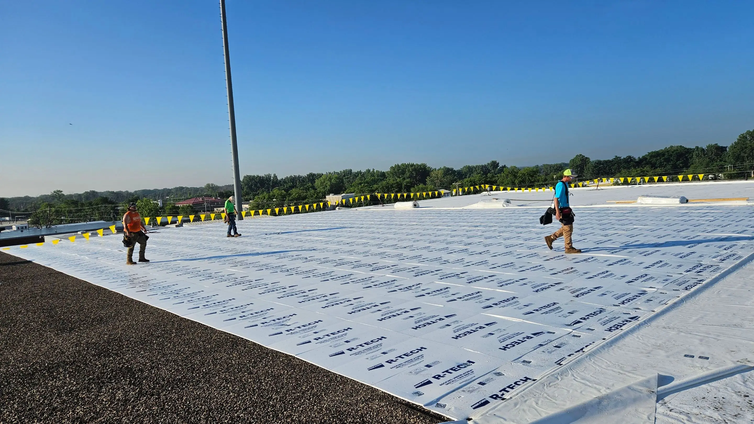 Crew laying fanfold insulation over an existing ballasted roof before the new membrane goes down, Davenport, Iowa